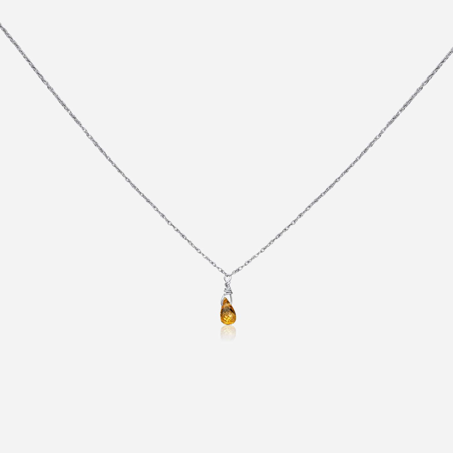 A gold-colored necklace with a teardrop-shaped orange pendant at the end, displayed against a white background.