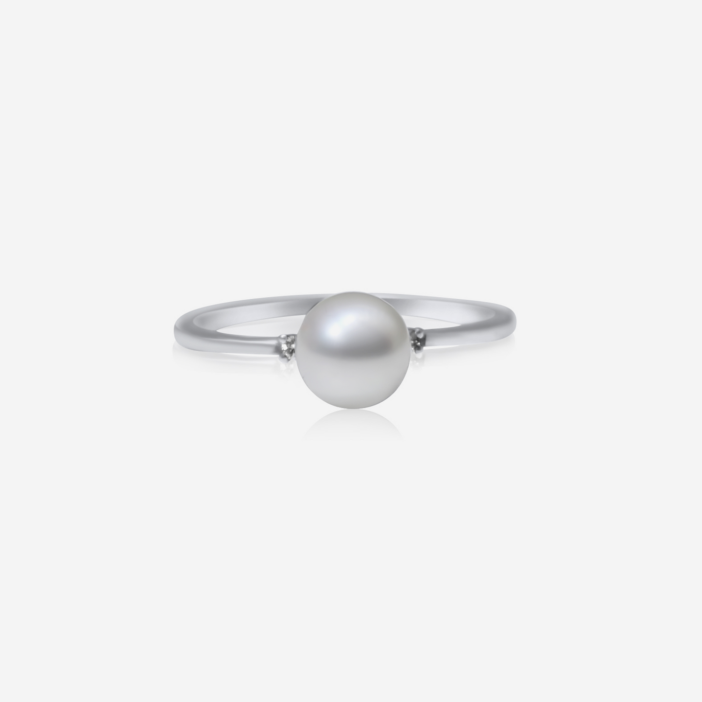 A gold ring with a central pearl and two side diamonds