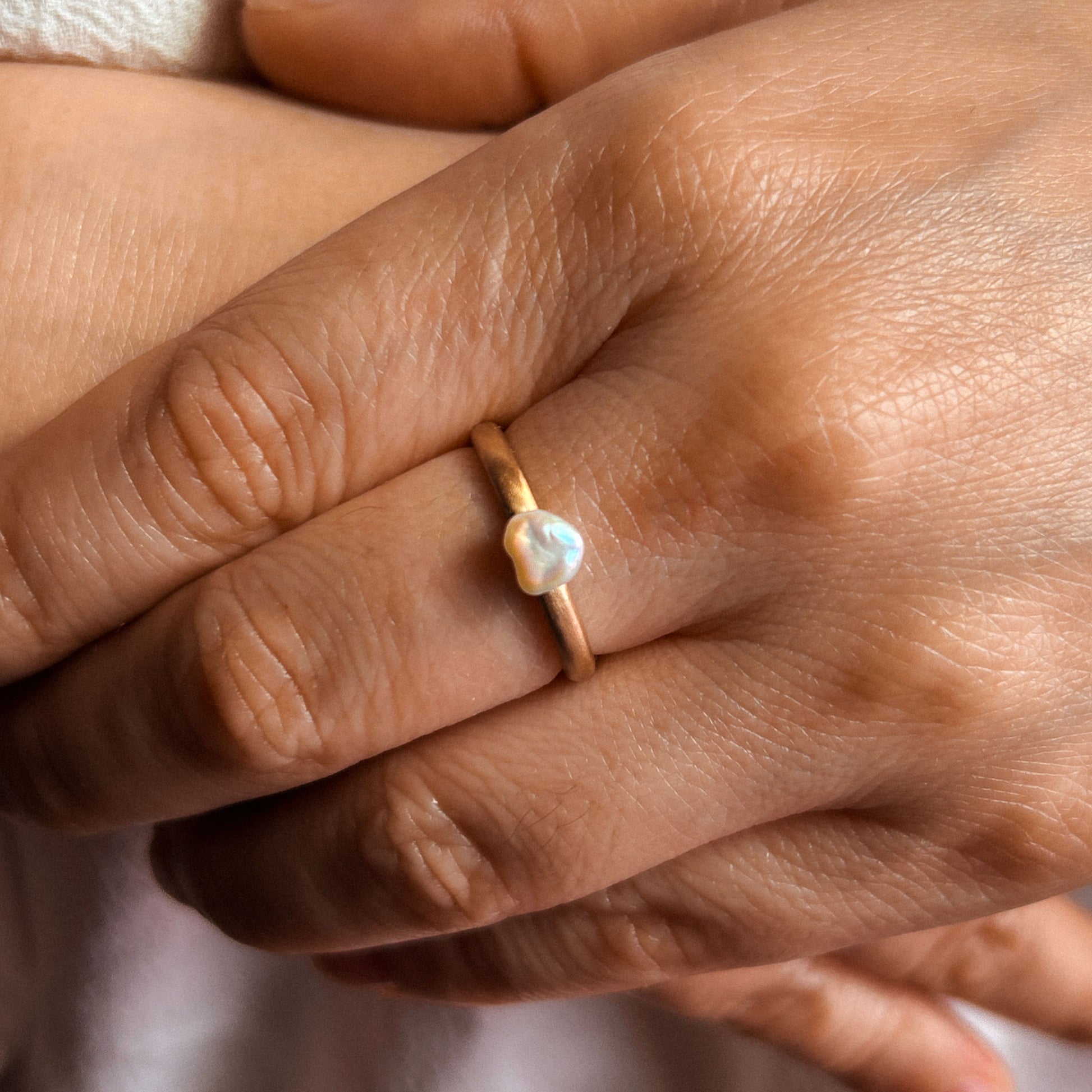 A Keshi pearl ring with a gold band, showcasing a unique and organic shape.