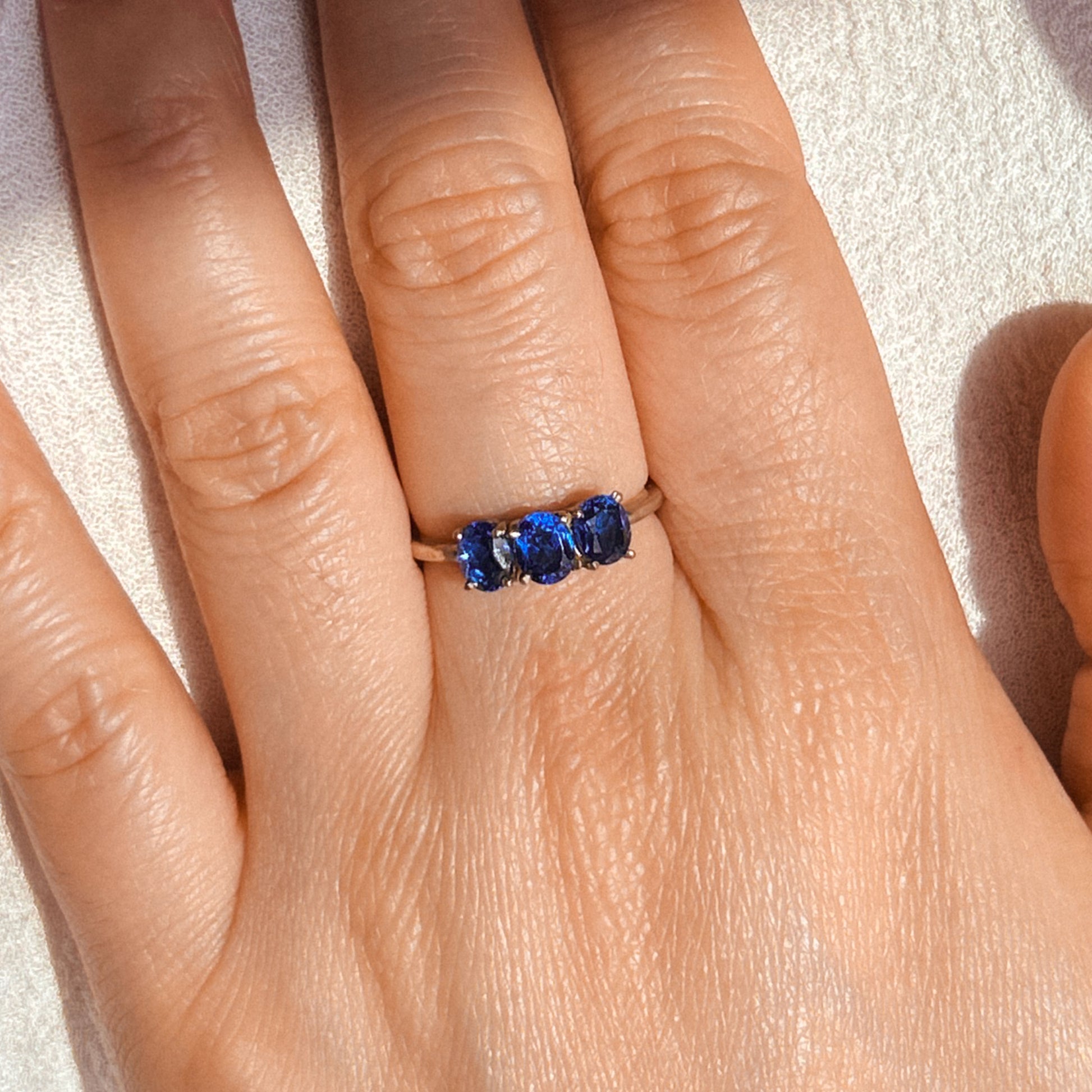 A Trio Sapphire Ring with three blue sapphire stones set in a gold band.