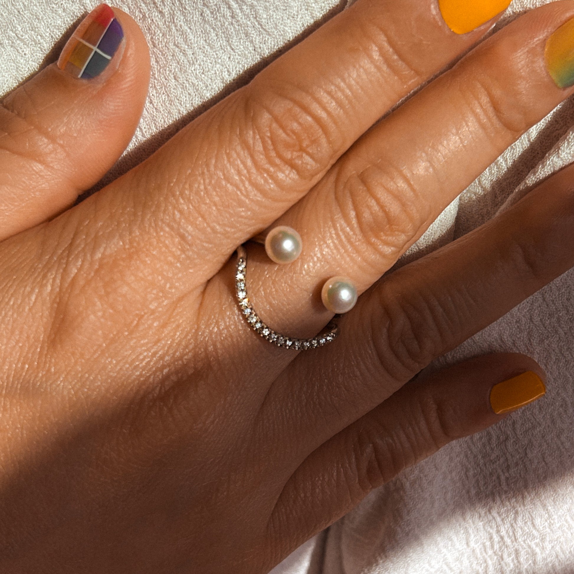 A 14 karat gold ring with a central Akoya pearl and white diamonds arranged in a semi-circular design, symbolizing a smile.