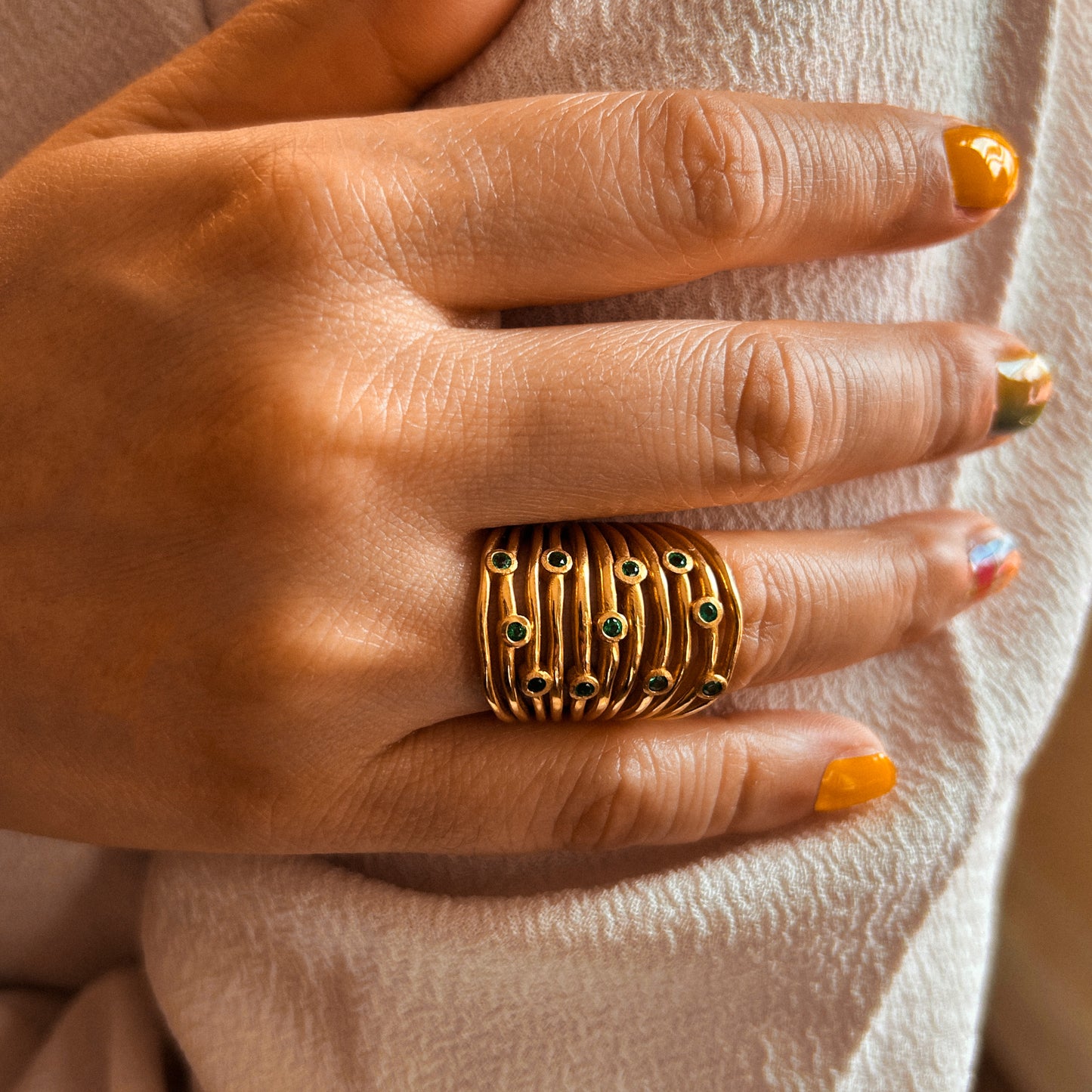 An 18-karat gold ring featuring multiple bands with small gemstones, presented against a white background.