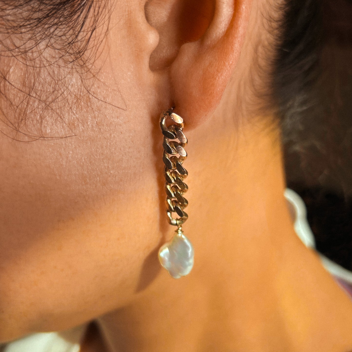 A pair of sterling silver chain earrings with pearl drops, laid out on a white surface.