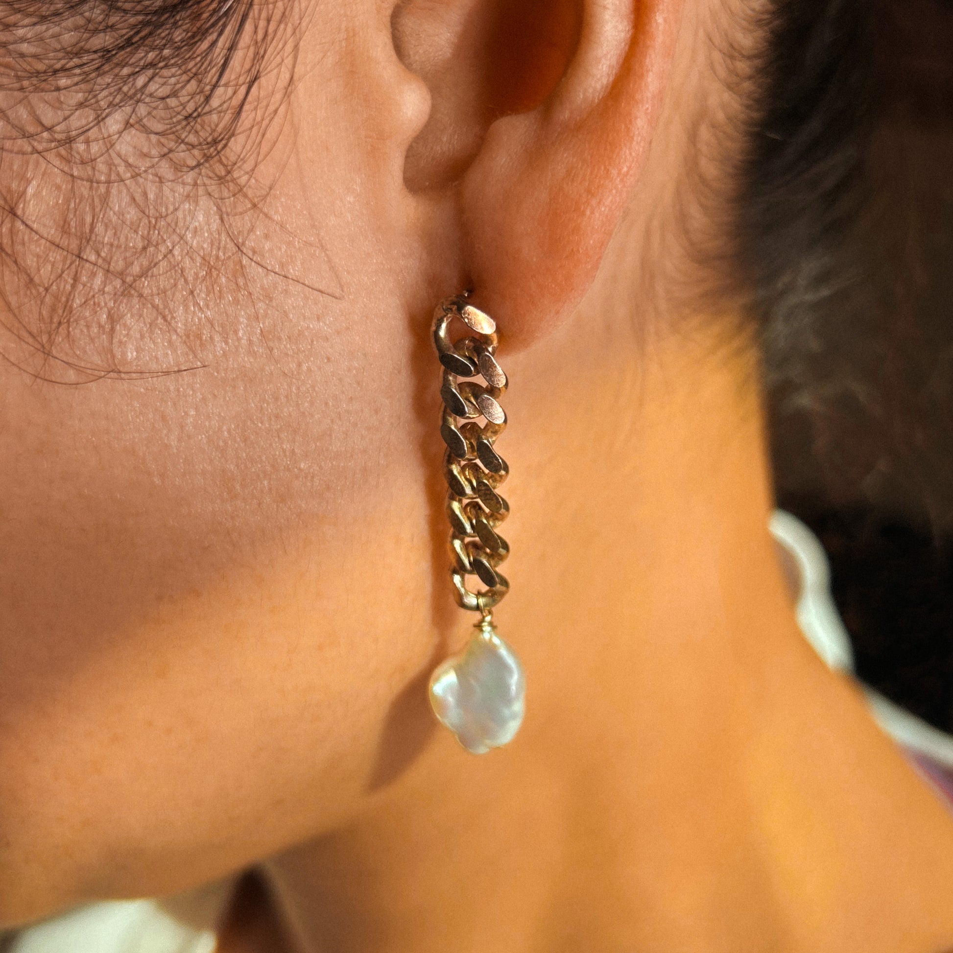 A pair of sterling silver chain earrings with pearl drops, laid out on a white surface.