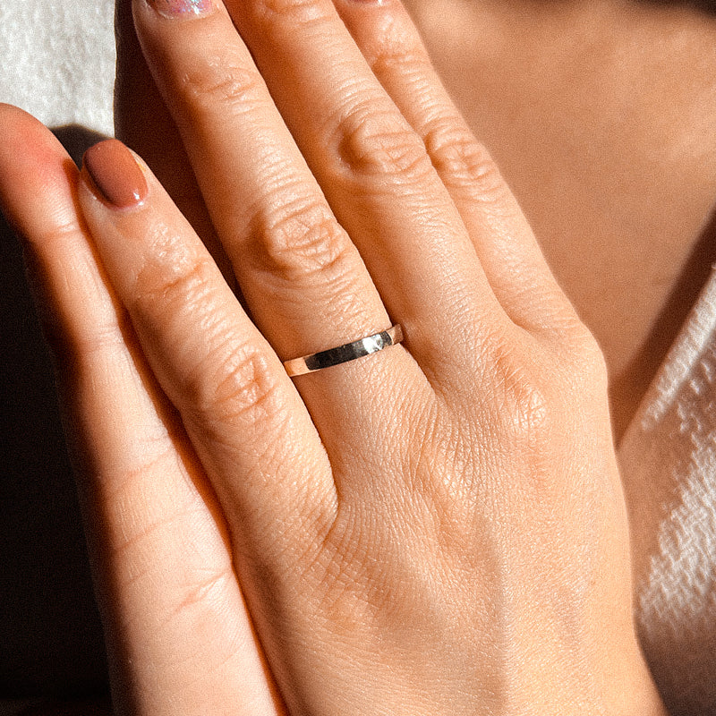 A gold-colored hammered finish wedding ring with a simple and elegant design.