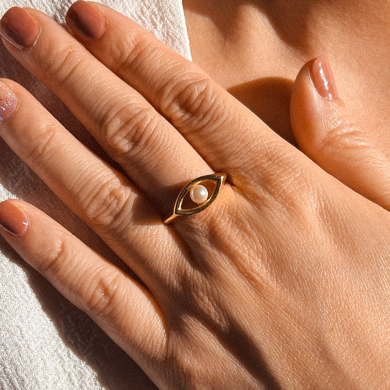 An 18-karat gold ring featuring a white Akoya pearl set in the shape of an eye.