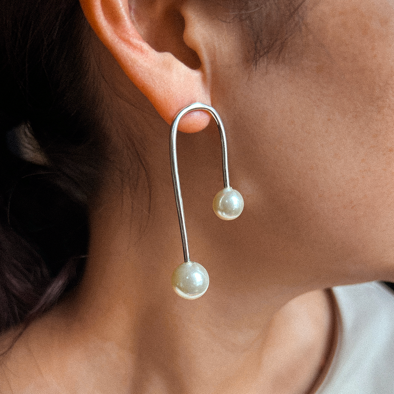 Earring with two pearl-like beads on a blurred background
