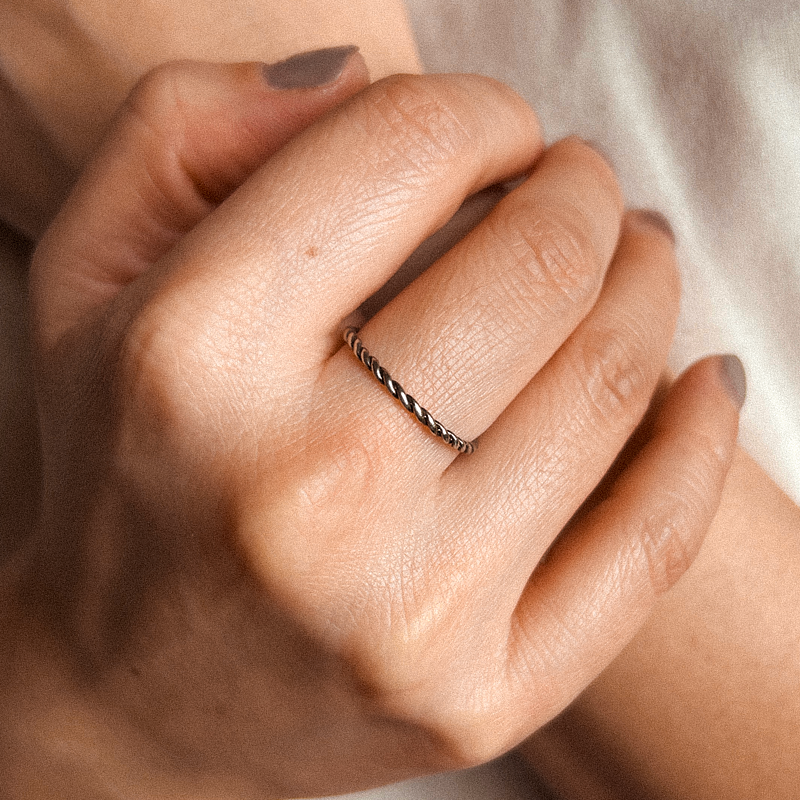 Close-up of a hand wearing a thin ring with a blurred background