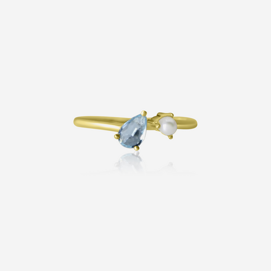 A gold ring featuring a pear-cut aquamarine and a smaller round Akoya pearl on a white background.