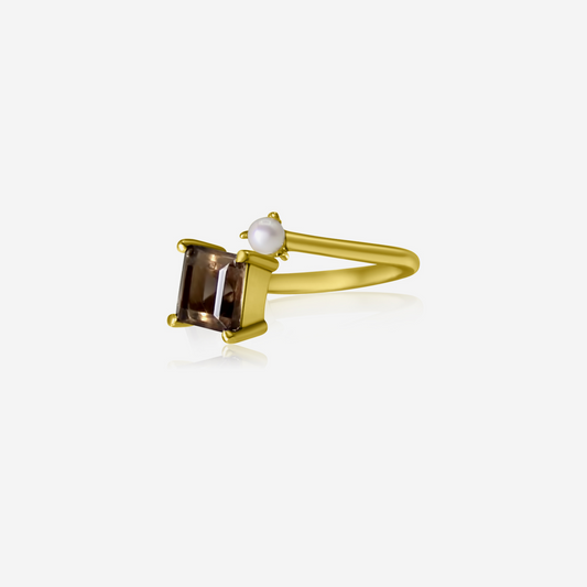 A gold ring featuring a princess cut smoky quartz and a small Akoya pearl on a white background.