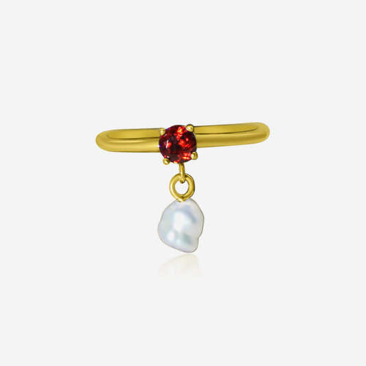 A gold ring with a radiant garnet gemstone and a pearl drop
