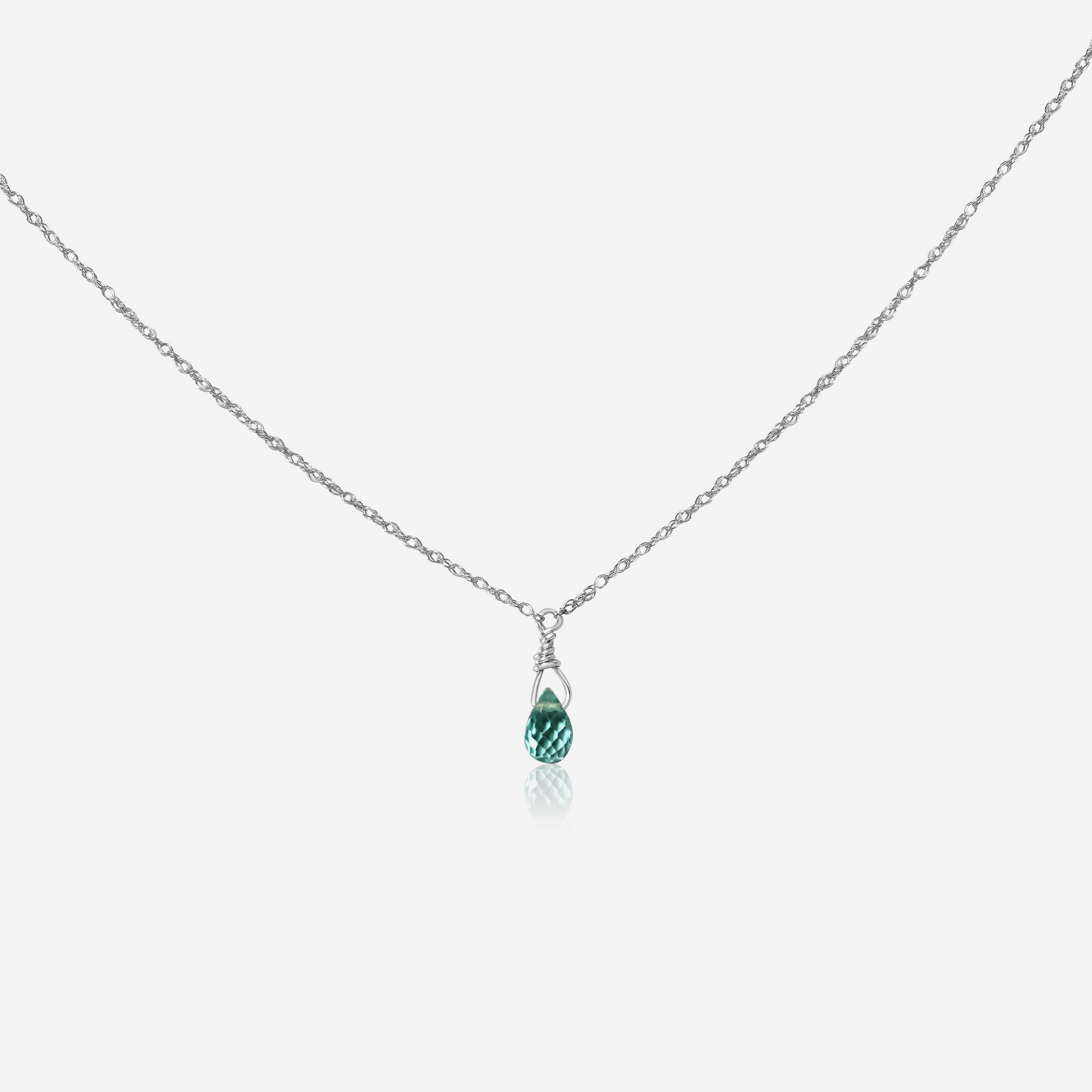 A green apatite drop necklace set in gold, suspended from a gold chain against a white background.