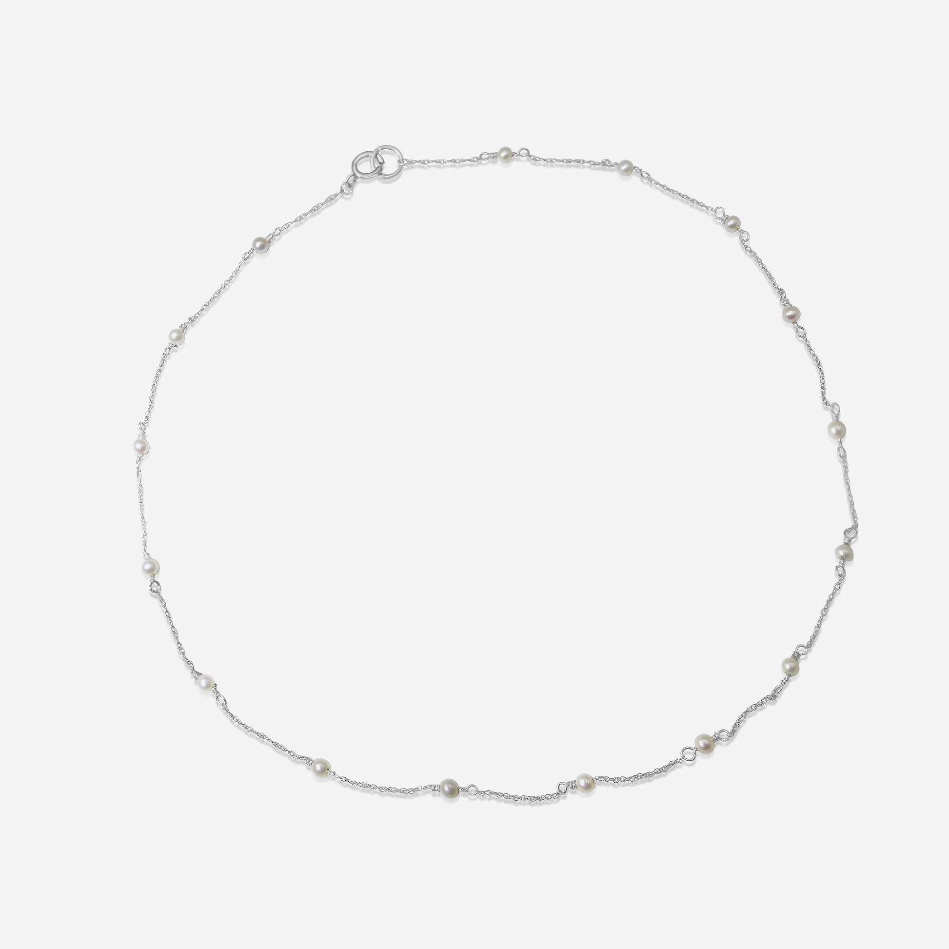 A delicate Tiny Akoya Pearl Necklace with small pearls on a gold-tone chain displayed against a white background.