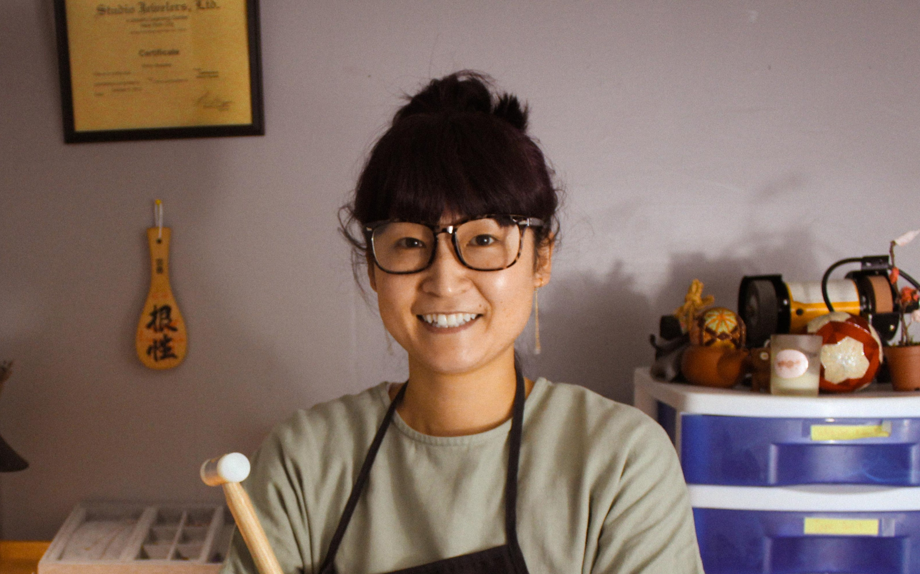 Person wearing glasses and an apron in a workshop setting
