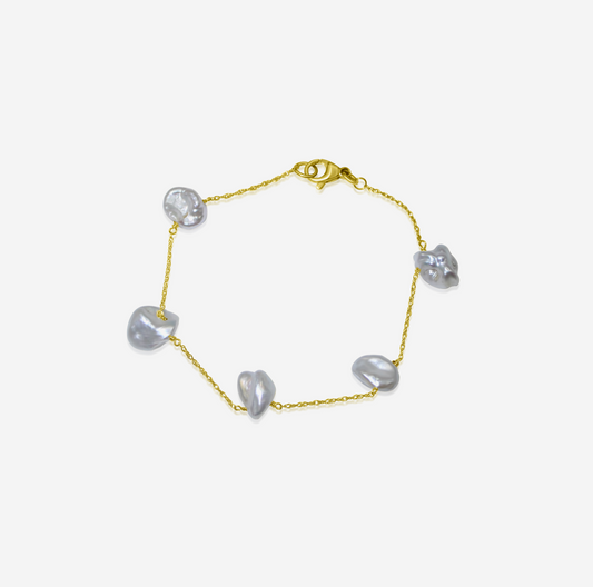 Gold bracelet with heart-shaped pearls on a light gray background
